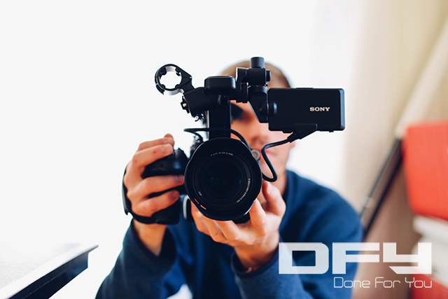 Man looking through viewfinder of video camera looking straight on